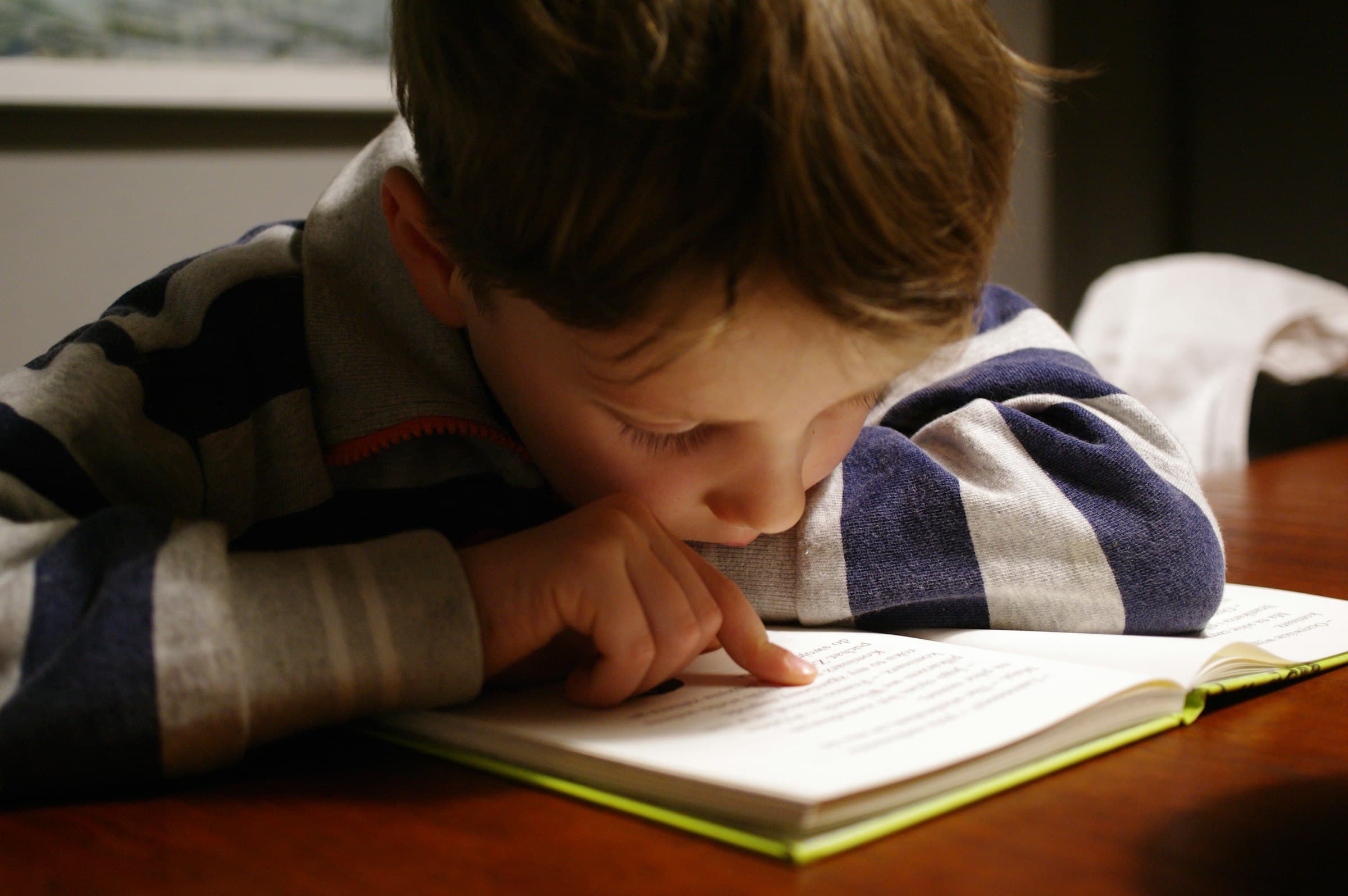 A child leaning over an open book at a table