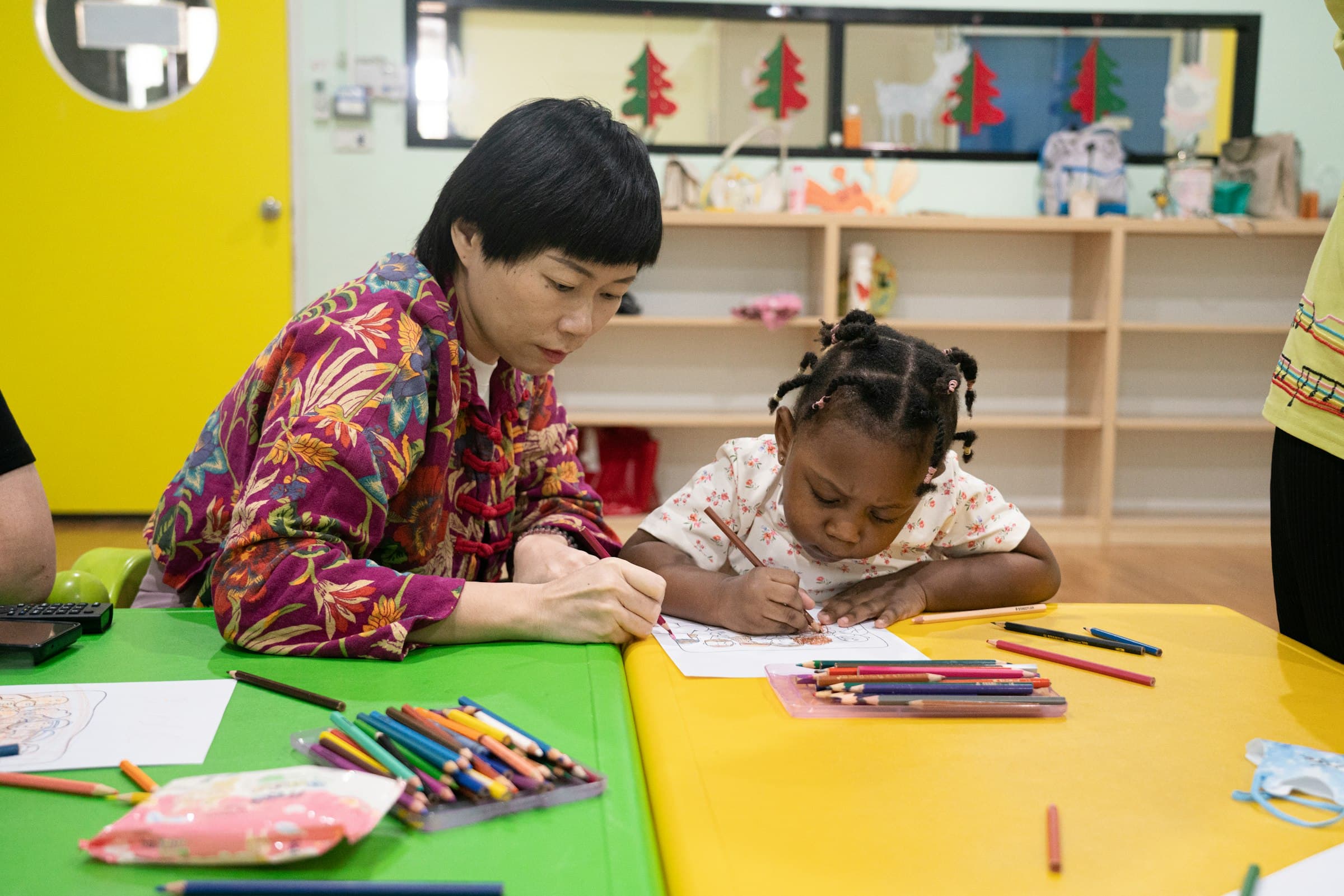 An adult drawing at a table alongside two young children